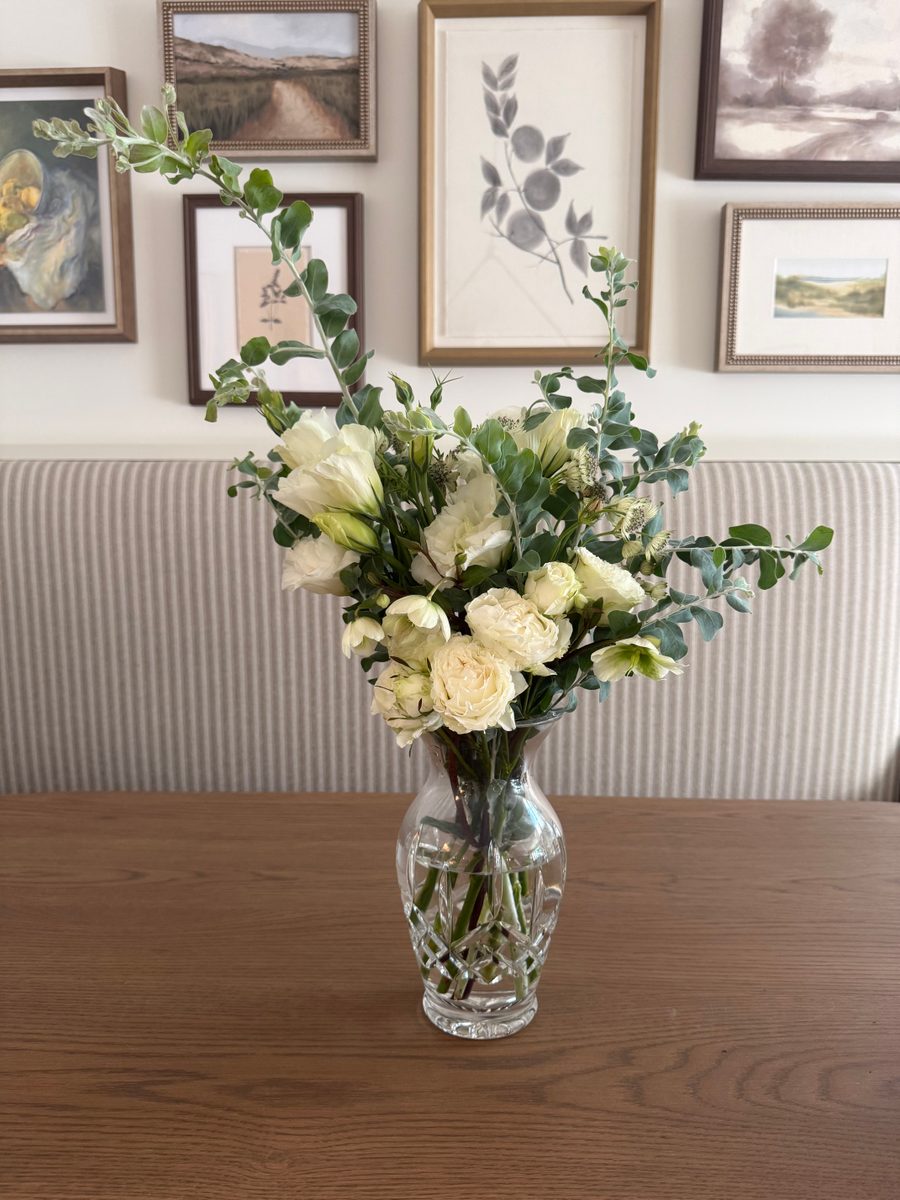 White roses and lisianthus with eucalyptus in a cut-glass vase