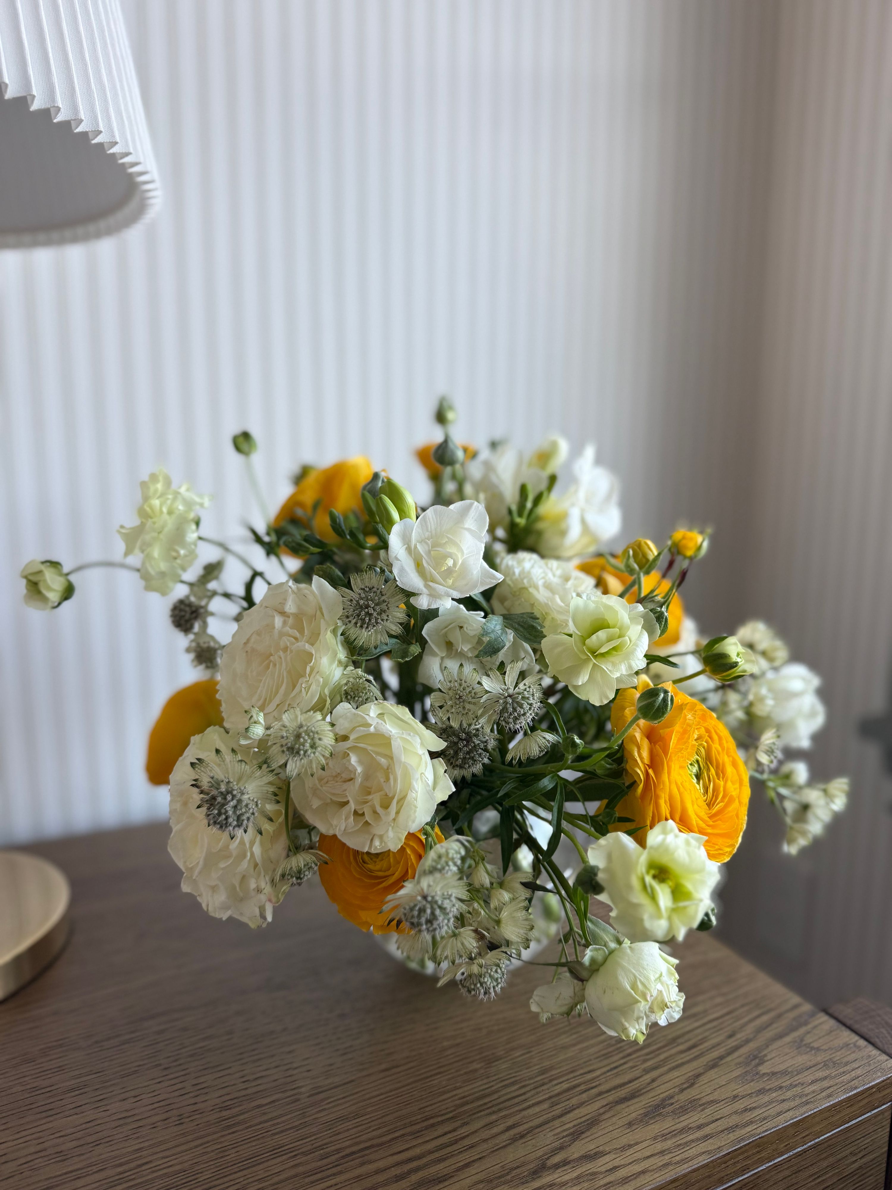 Yellow ranunculus, white roses and astrantia in a low arrangement