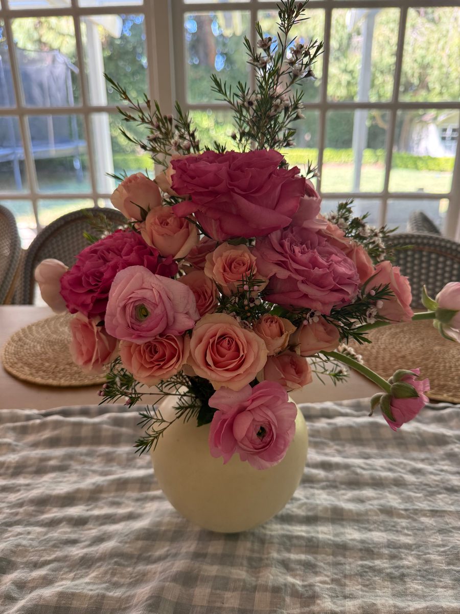 Pink roses, ranunculus and spray roses in a pale yellow ceramic vase
