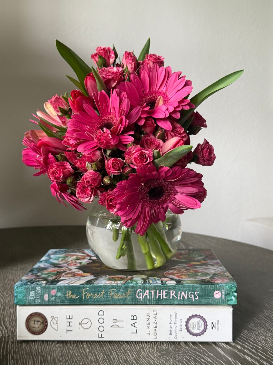 Hot pink gerbera daisies and magenta spray roses in a round glass bowl