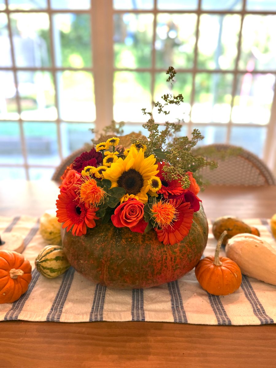Autumn arrangement with a sunflower and orange gerbera in a carved pumpkin