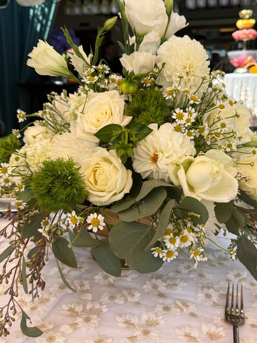 White roses, dahlias and chamomile with eucalyptus in a low footed bowl