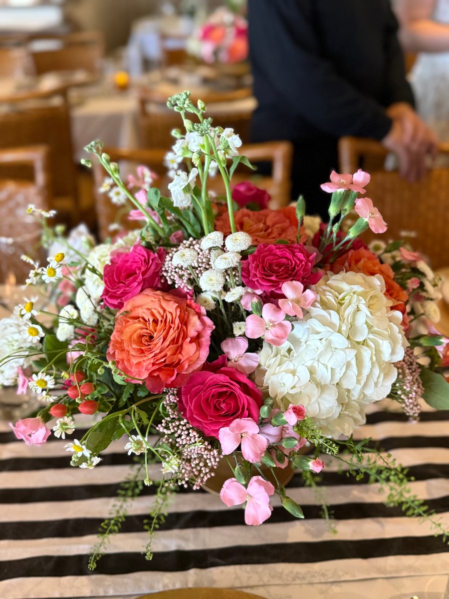 Large event centerpiece with white hydrangea and orange and magenta garden roses