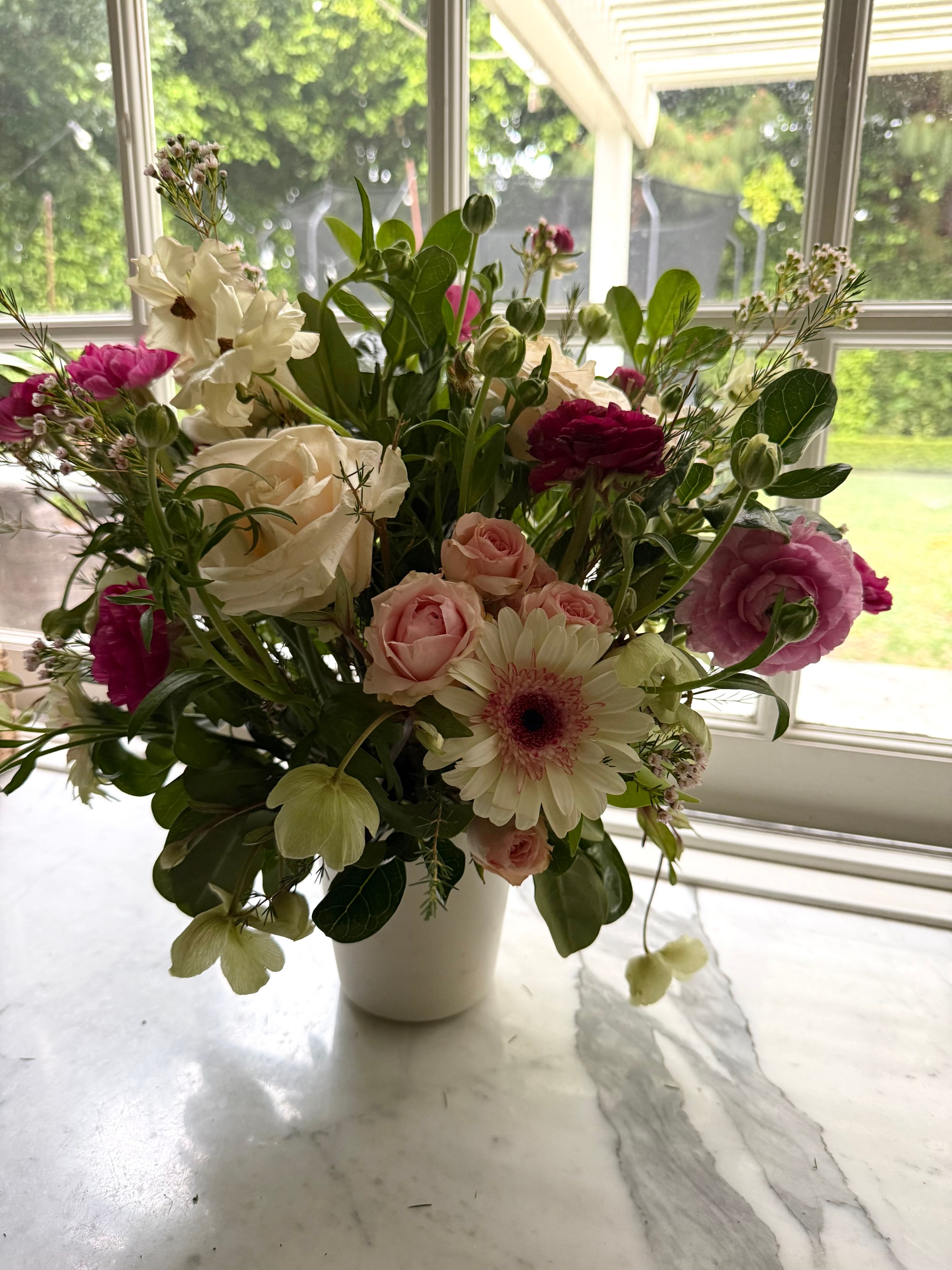 Blush arrangement with cream roses, pink gerbera and hellebore in a white pot